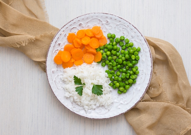 Rice with vegetables and parsley on plate with cloth