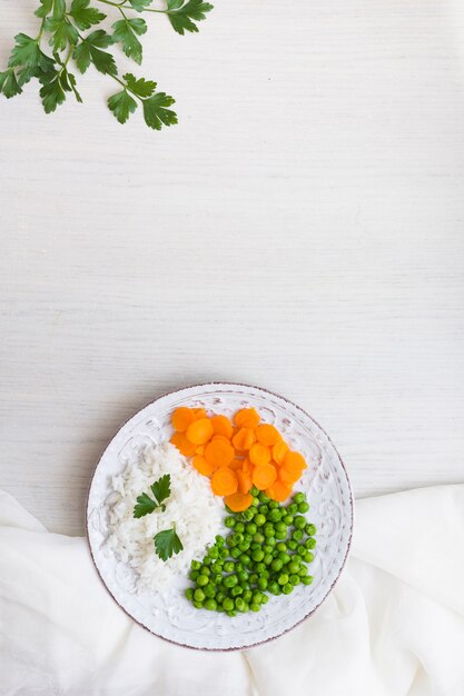 Rice with vegetables and parsley on plate with white cloth