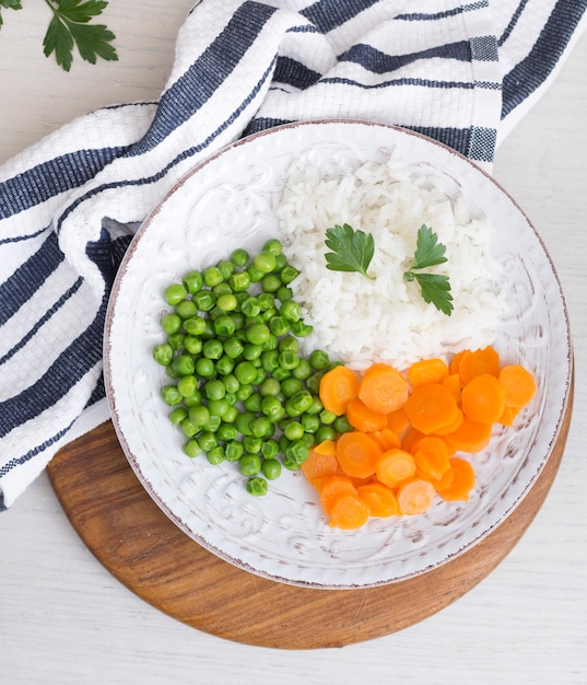 Riso con verdure e prezzemolo sul tovagliolo vicino tavola di legno