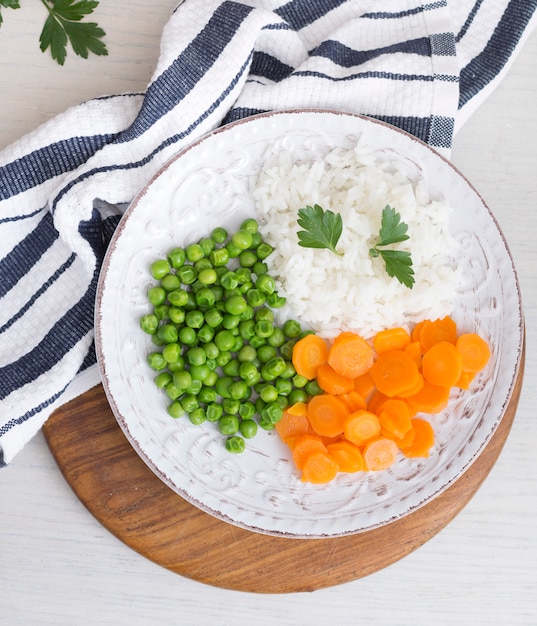 Rice with vegetables and parsley on wooden board near napkin 