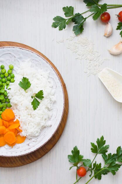 Rice with vegetables on wooden board near garlic