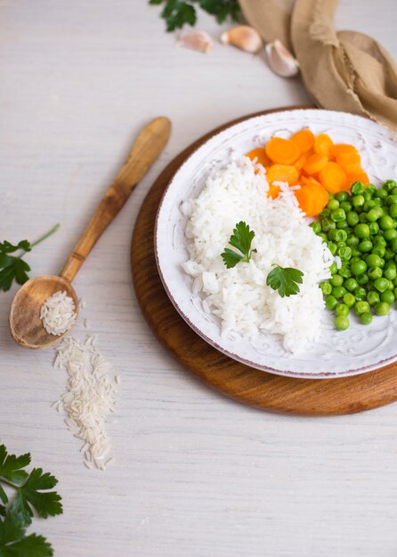 Rice with vegetables on wooden board near spoon 