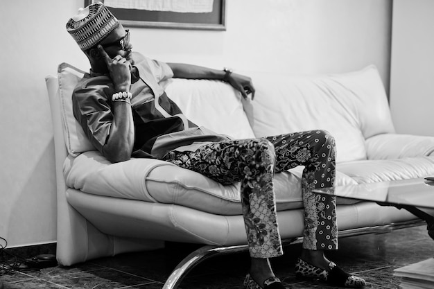 Богатый африканец сидит на диване в своей квартире Портрет успешного чернокожего мужчины в помещении