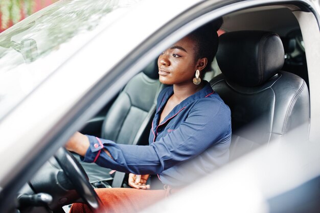 Rich business african woman sit on driver seat at silver suv car with opened door