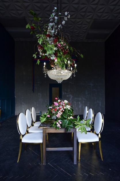 Free photo rich christal chandelier hangs over the dinner table with red roses and greenery