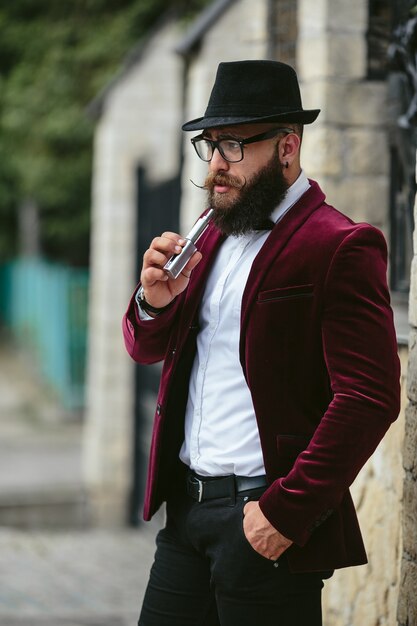 A rich man with a beard smokes electronic cigarette