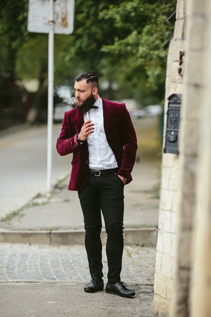 A rich man with a beard smokes electronic cigarette