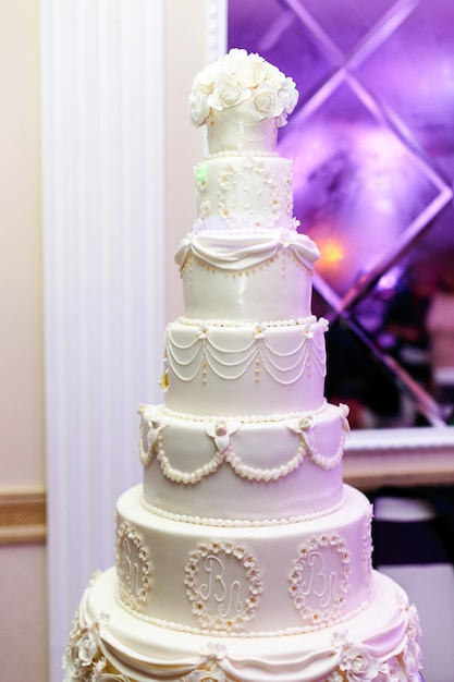 Богатый уставший свадебный торт, украшенный инициалами молодоженов