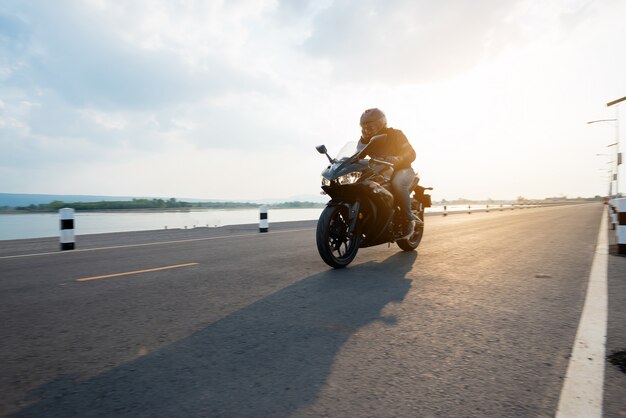 Наездник на мотоцикле по дороге катается. весело проводя время на пустой дороге