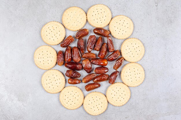 A ring of biscuits surrounding a pile of dates on marble surface