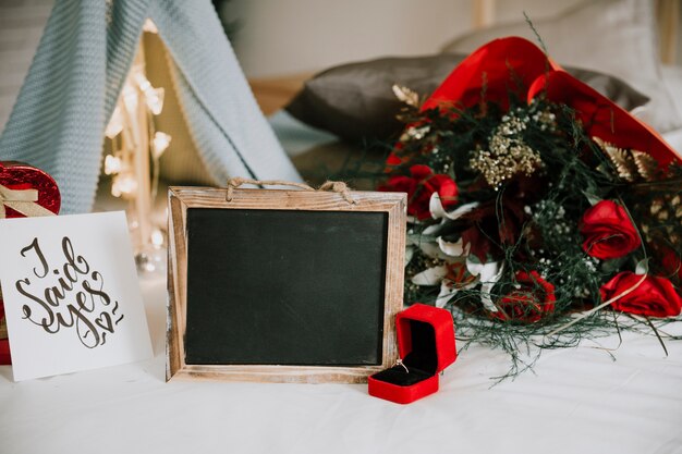 Ring and blackboard near bouquet and gifts