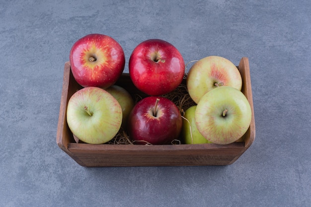 Ripe apples in box on marble table.