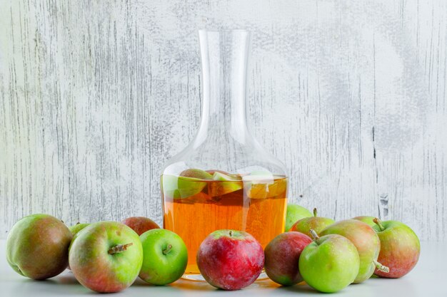 Ripe apples with drink on white and grungy, side view.