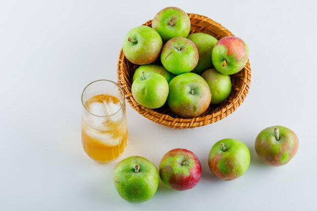 Ripe apples with juice in a wicker basket on white, high angle view.