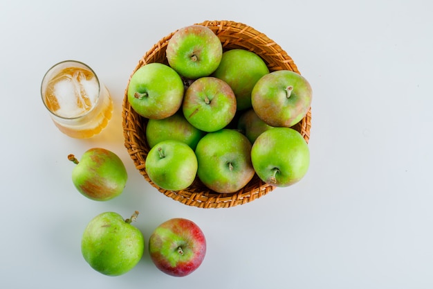 Ripe apples with juice in a wicker basket on white.