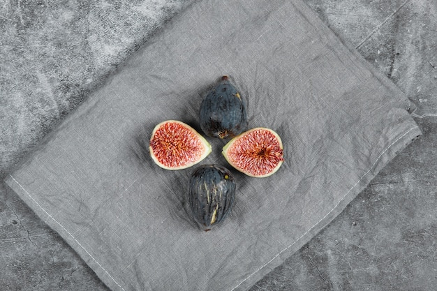 Fichi neri maturi su uno sfondo di marmo con una tovaglia grigia. foto di alta qualità