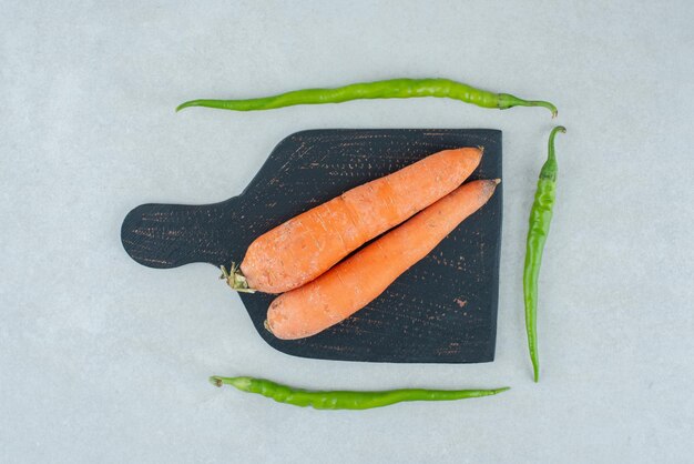 Ripe carrots and peppers on dark board.