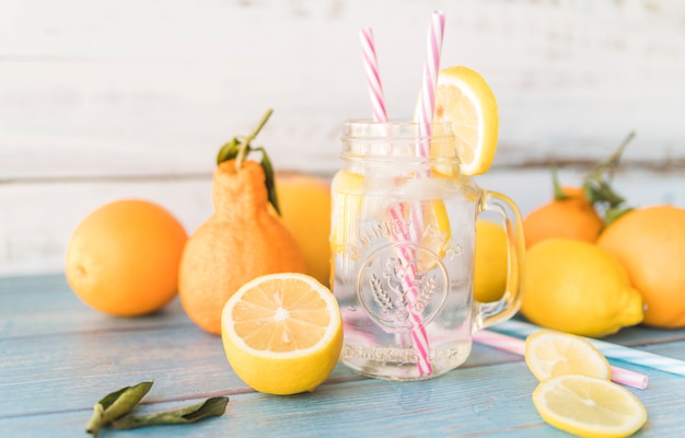 Ripe citrus fruits and straws in jar