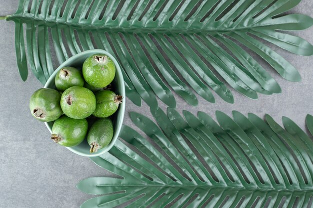 Ripe feijoa fruits in blue bowl with leaves. High quality photo