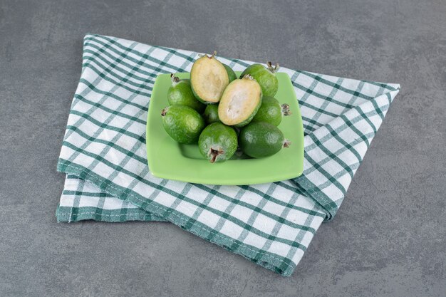 Зрелые плоды фейхоа на зеленой тарелке. Фото высокого качества