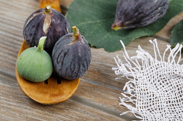 Ripe figs with a wooden spoon on wooden table.