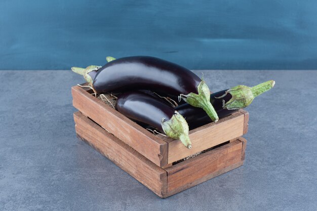 Ripe fresh eggplants in wooden box.