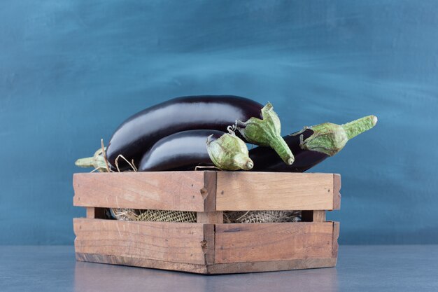 Ripe fresh eggplants in wooden box.