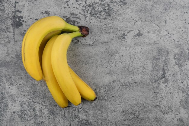 Ripe fresh healthy banana cluster on stone table.