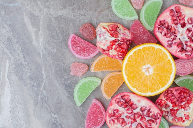 Ripe fruits with sweet marmalade on marble background.