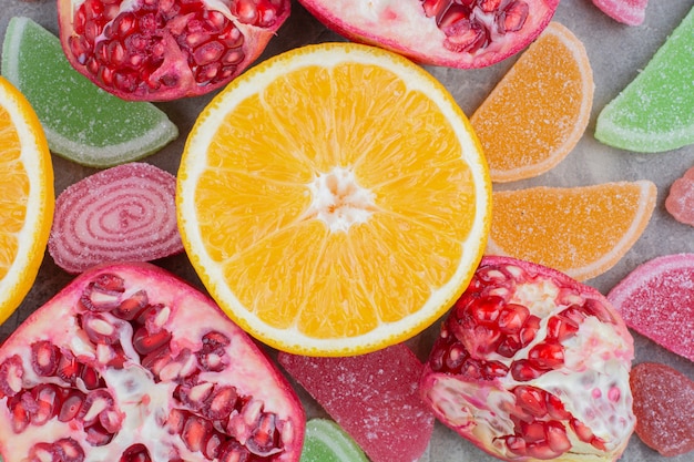 Ripe fruits with sweet marmalade on marble background.