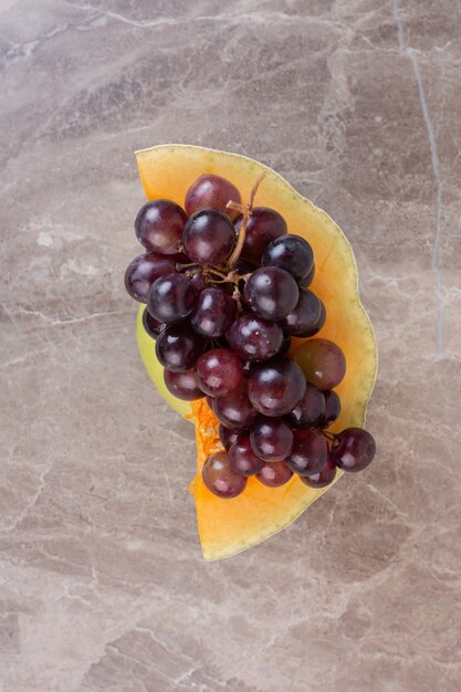 Ripe grape on sweet pumpkin on marble surface