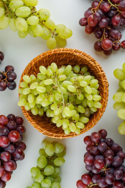 Ripe grapes in a wicker basket on a white.