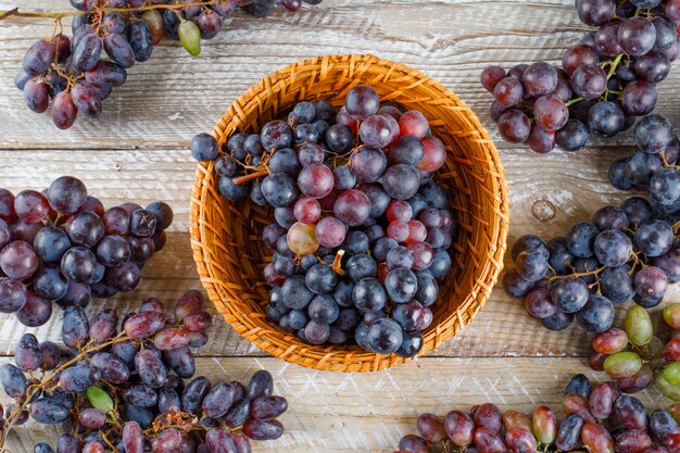 Ripe grapes in a wicker basket on a wooden background. flat lay.