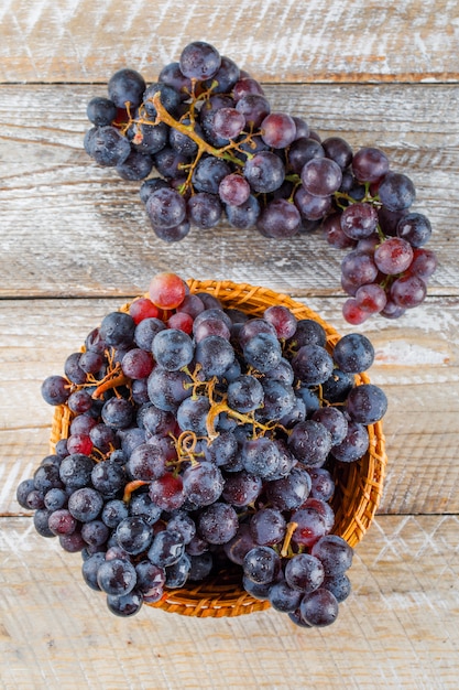 Ripe grapes in a wicker basket on a wooden background. top view.