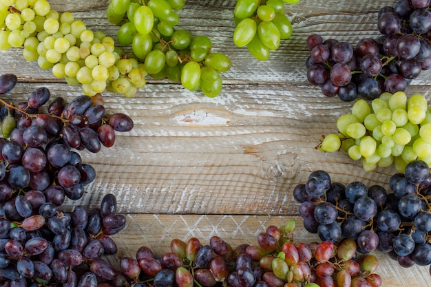 Ripe grapes on wooden background, flat lay.