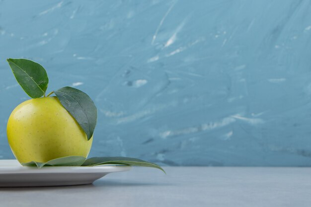 白い皿に熟した青リンゴ。