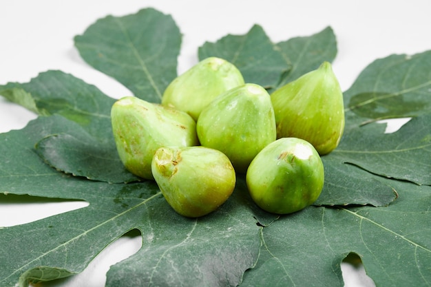 Ripe green figs with leaves on white background. High quality photo