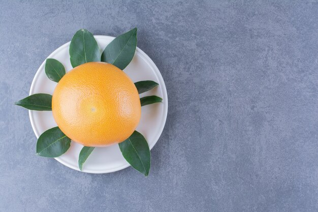 대리석 테이블에 접시에 잎과 익은 육즙 오렌지.