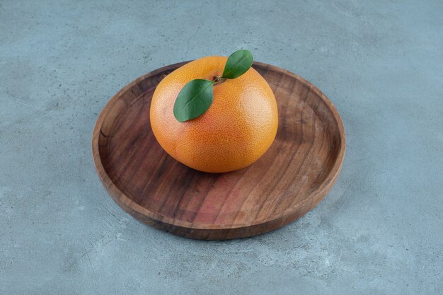 Ripe juicy orange on a wooden plate, on the marble background. High quality photo