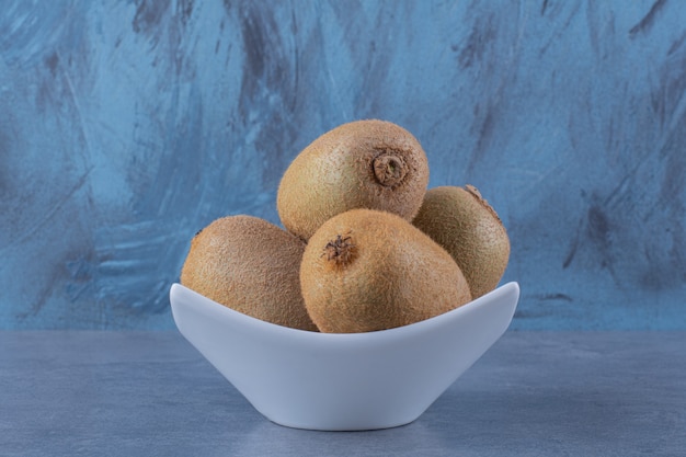 Ripe kiwi fruits in a bowl on the dark surface