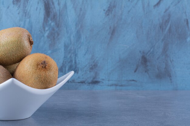 Ripe kiwi fruits in a bowl on marble table.