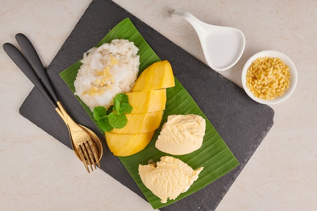 Спелое манго и липкий рис, мороженое с кокосовым молоком на каменной поверхности, тайский сладкий десерт в летний сезон. Тропический фрукт. Фруктовый десерт. вид сверху.