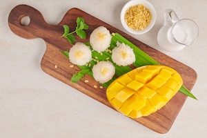 Ripe mango and sticky rice with coconut milk on wood plate on stone surface, tropical fruit.  dessert fruit. thai sweet dessert on summer season.