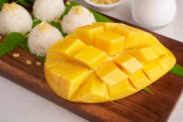 Спелое манго и липкий рис с кокосовым молоком на деревянной тарелке на каменной поверхности, тропические фрукты. Фруктовый десерт. Тайский сладкий десерт в летний сезон.