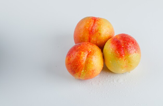 Ripe nectarines on white surface, high angle view.