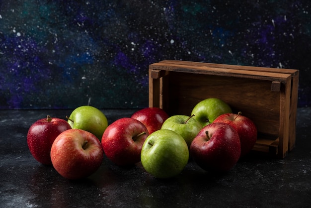 Бесплатное фото Спелые органические яблоки из деревянной коробки на черной поверхности. .