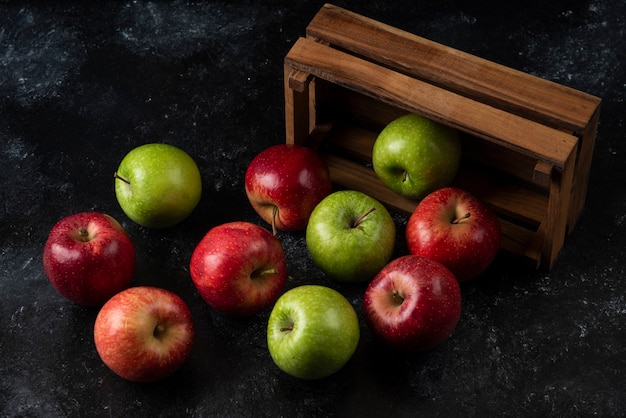 Ripe organic apples out of wooden box on black surface. .