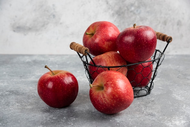 Ripe organic red apples in metal basket on black.