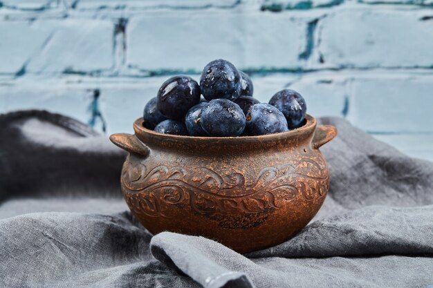 Ripe plums in a bowl on gray tablecloth