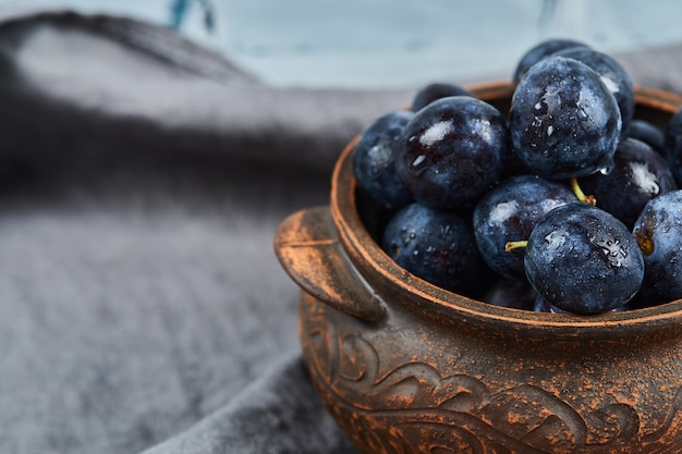 Foto gratuita prugne mature in una ciotola sulla tovaglia grigia